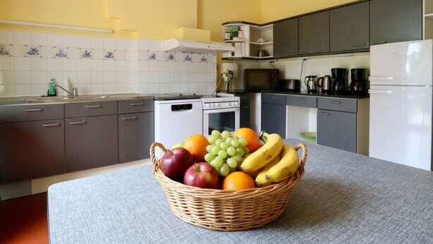 Une cuisine avec un panier de fruits sur le comptoir, un four à micro-ondes, une machine à café et des placards.