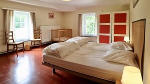 Une chambre à coucher avec un lit, une chaise, un radiateur et une fenêtre.