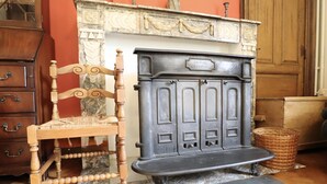 Une pièce avec une chaise en bois, une cheminée et une commode.