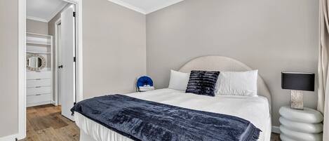 A bedroom with a bed, bedside table, lamp, and a walk-in closet.
