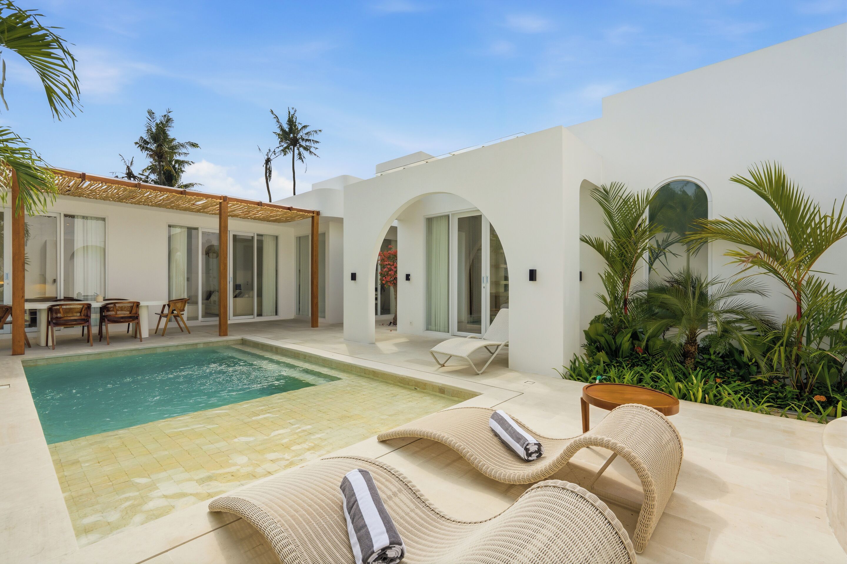 A modern outdoor pool area with lounge chairs and a dining setup.