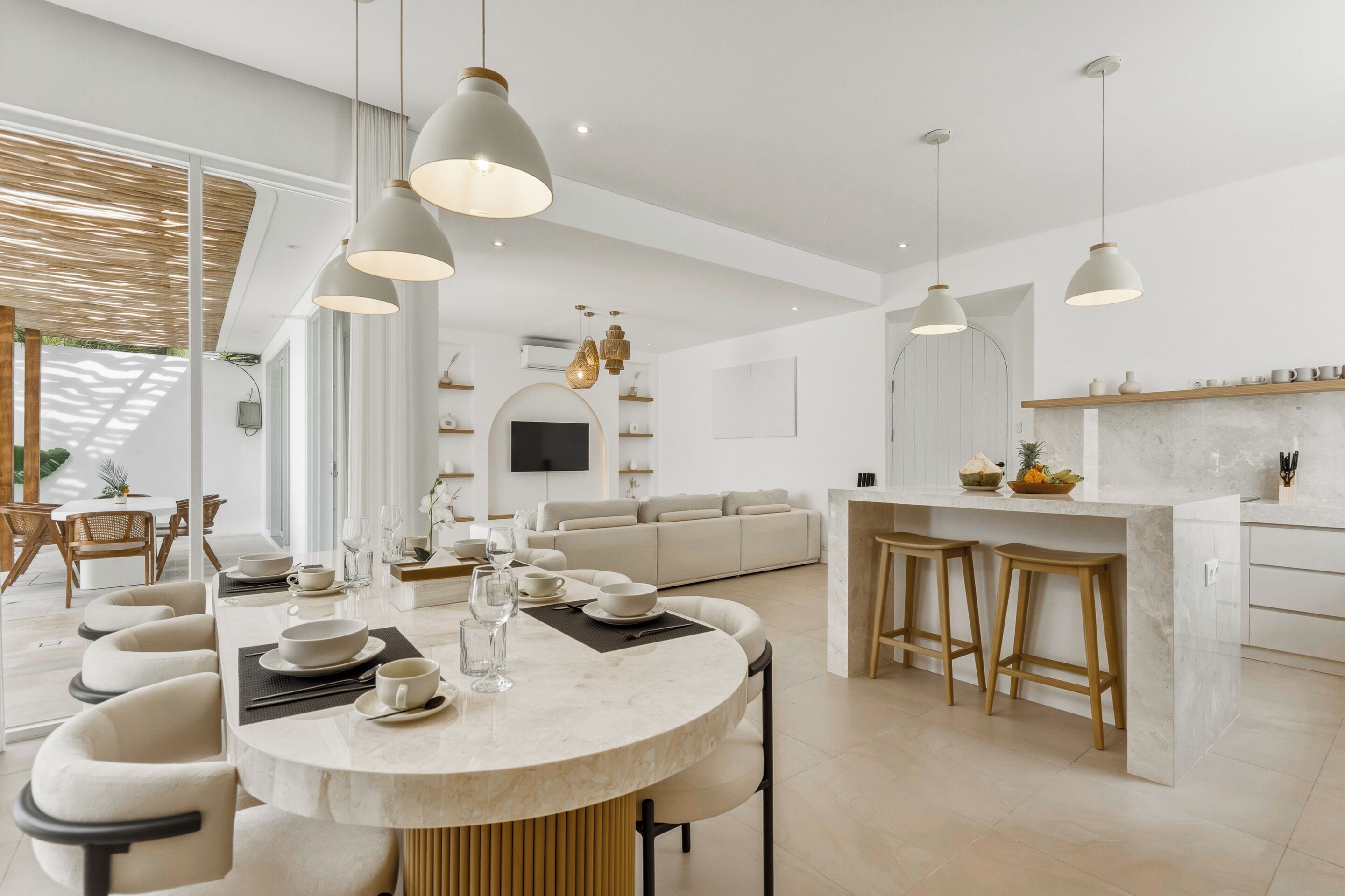 Una cocina moderna con una isla central, iluminación colgante y un comedor con una mesa redonda.
