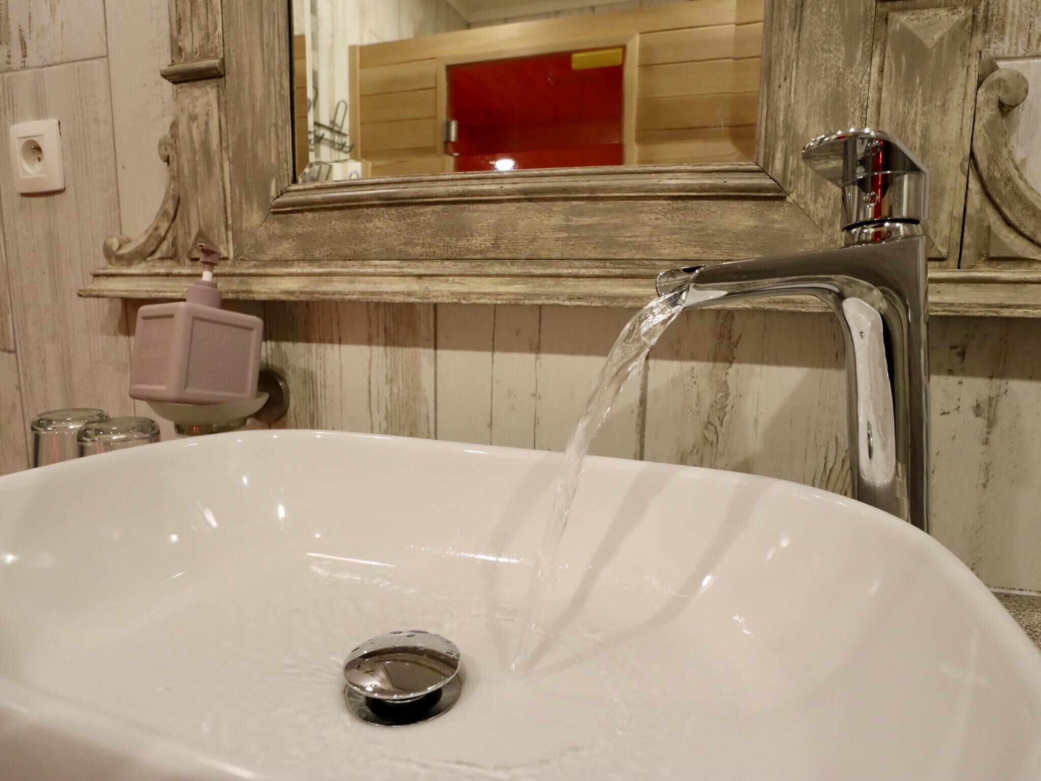 Une salle de bain avec un lavabo blanc, un miroir et un meuble rouge.