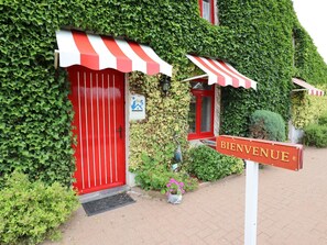 Ein Gebäude mit roter Tür und Streifenmarkise, einem 'Bienvenue'-Schild und einem 'Wallonie'-Schild.
