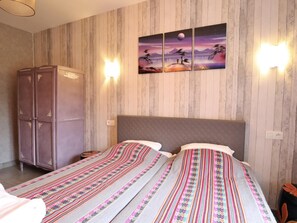 Ein Hotelzimmer mit einem Bett, zwei Nachttischen, einem Kleiderschrank und einer Wand mit drei Bildern.