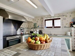 Eine Küche mit Gaskochfeld, Backofen, Mikrowelle und einer Obstschale auf der Arbeitsfläche.