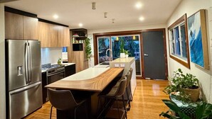 Une cuisine moderne dotée d’un îlot central, d’appareils électroménagers en acier inoxydable et d’un revêtement de sol en bois.