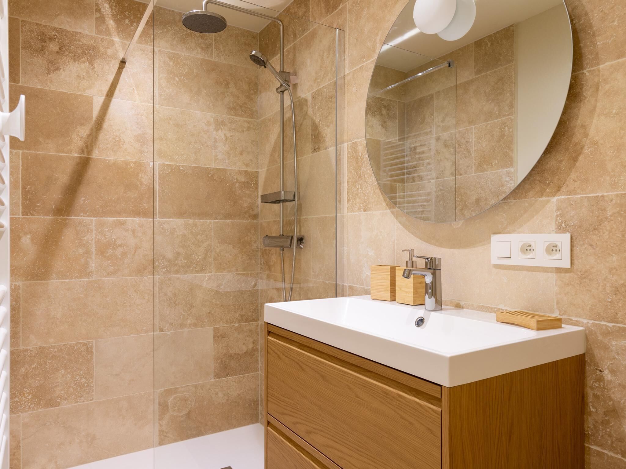 A modern bathroom with a shower, a sink, and a mirror.