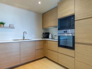 A modern kitchen with wooden cabinets, a stainless steel sink, and built-in appliances including a microwave and oven. - A beautifully renovated flat on the Zeedijk (Blankenberge)