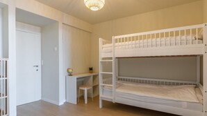 Une chambre avec un lit superposé, un bureau et une chaise, un globe terrestre et une porte.