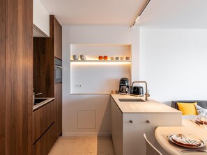 Eine kompakte Küche mit eingebautem Ofen, einer Kaffeemaschine und einem Toaster auf der Arbeitsfläche.