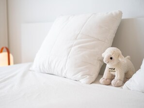 A bed with white bedding and pillows, a plush toy, and a white bag on the side. - Stylish apartment with dune view near Idesbald (Sint-Idesbald)