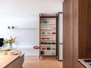 A modern kitchen with wooden cabinets, a dining table set with plates and glasses, and a vase of flowers. - Stylish apartment with dune view near Idesbald (Sint-Idesbald)