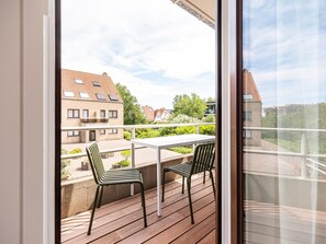 A balcony with a table and chairs, overlooking a residential area with houses and greenery.