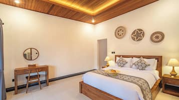 A hotel room with a wooden ceiling, a bed with patterned bedding, a desk with a chair, and decorative wall art.
