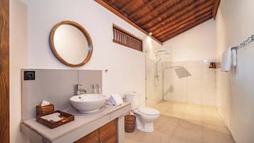 A bathroom with a wooden ceiling, a round mirror, a sink, a toilet, and a shower area.
