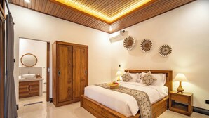Een hotelkamer met een houten bed, een badkamer met een ronde spiegel en decoratieve wandkunst.