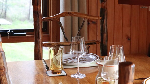 A wooden dining table with a chair, a plate, and several glasses and a pitcher. - Howqua Hideaway - cozy cabin with fireplace (Howqua)