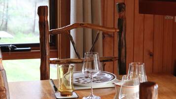 A wooden dining table with a chair, a plate, and several glasses and a pitcher.