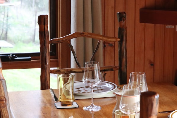 A wooden dining table with a chair, a plate, and several glasses and a pitcher.