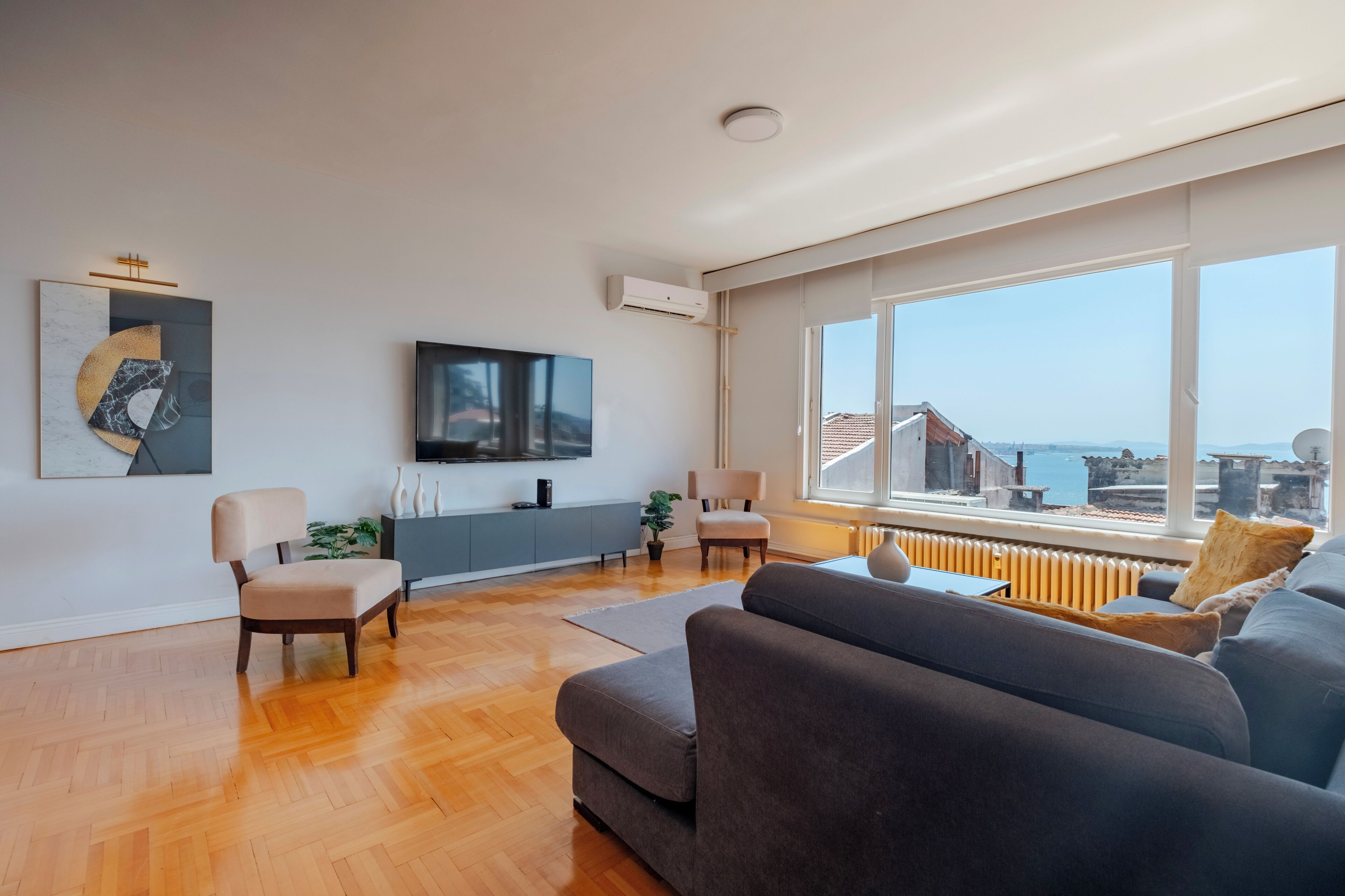 A modern living room with a large window, a flat-screen TV, a sofa, and a chair.