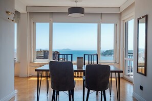 A dining area with a table and chairs, large windows with a view of the sea and distant land, and a pendant light above. - Bosphorus Panorama – Luxury 5BR Apartment with Balcony & AC (İstanbul)