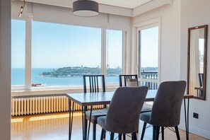 A dining area with a view of the sea, large windows, and a radiator under the table. - Bosphorus Panorama – Luxury 5BR Apartment with Balcony & AC (İstanbul)