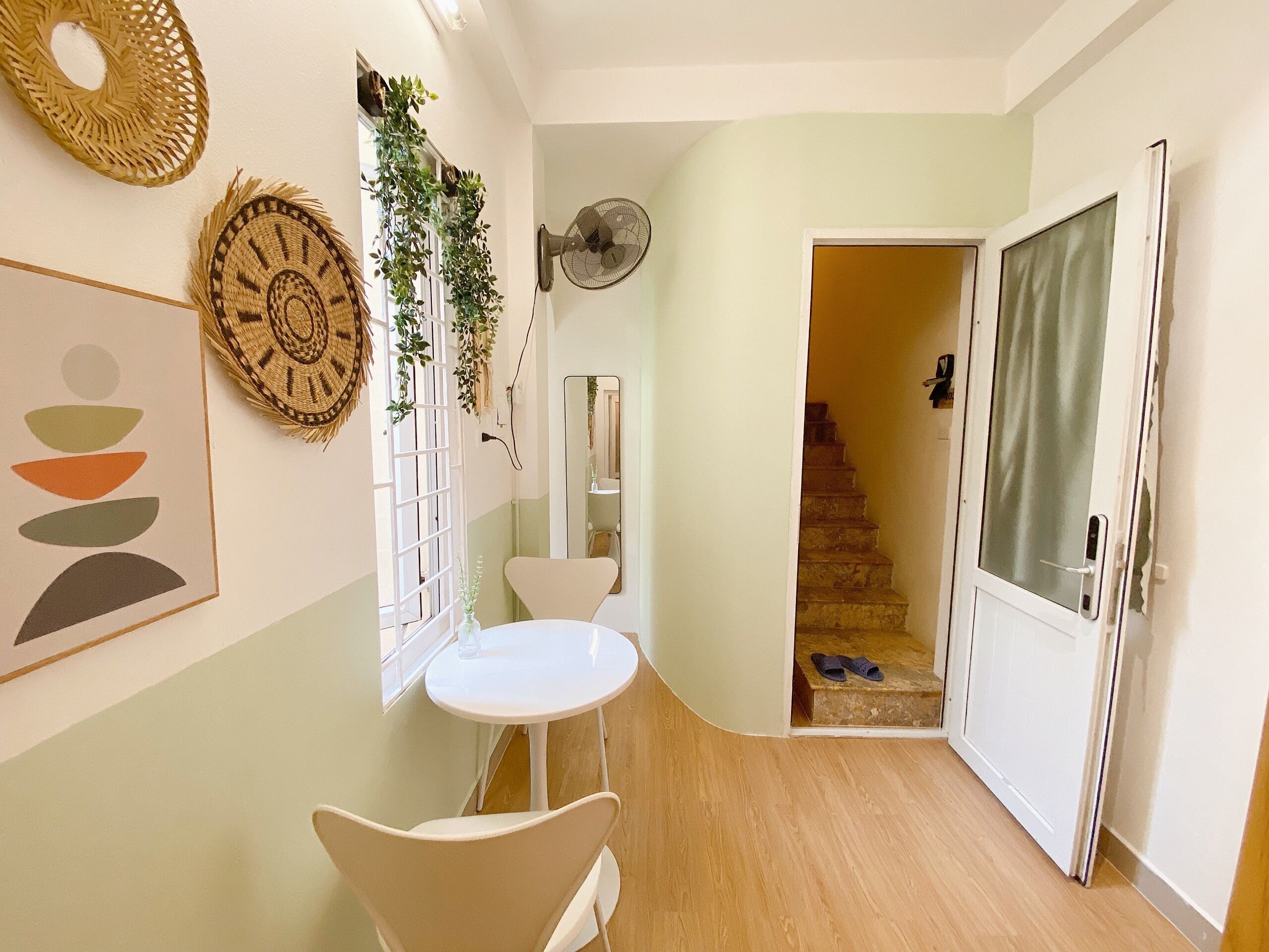 A hallway with a white table and chairs, a fan, and a staircase leading to another room.