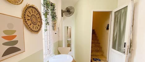 A hallway with a white table and chairs, a fan, and a staircase leading to another room.