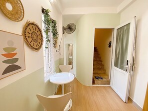 A hallway with a white table and chairs, a fan, and a staircase leading to another room. - Big Bedroom for max 4, Hanoi Old Quarter, Best Deal w/ Private Bath, Free Wash (Hà Nội)