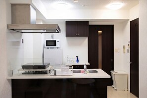 Una cocina compacta equipada con microondas, refrigerador pequeño, pileta y lavavajillas.