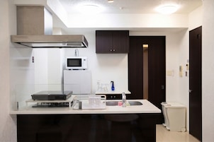 Una cocina compacta equipada con microondas, refrigerador pequeño, pileta y lavavajillas.