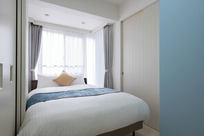 Una habitación de hotel con cama, cortinas, ventana y puerta.