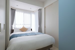 Una habitación de hotel con cama, cortinas, ventana y puerta.