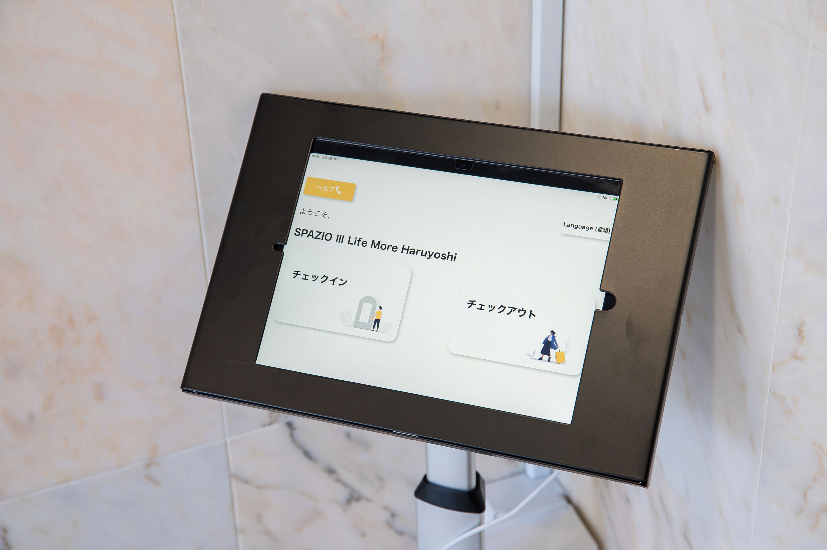 A digital kiosk with a screen displaying text in Japanese, possibly for hotel services or information.