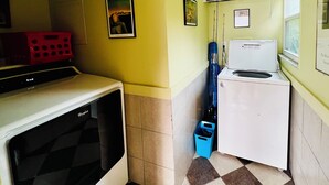 Una cocina compacta con lavavajillas Whirlpool, un refrigerador pequeño y un cubo de basura azul.