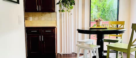 A modern kitchen with dark wood cabinets, a white countertop, and a hanging plant.