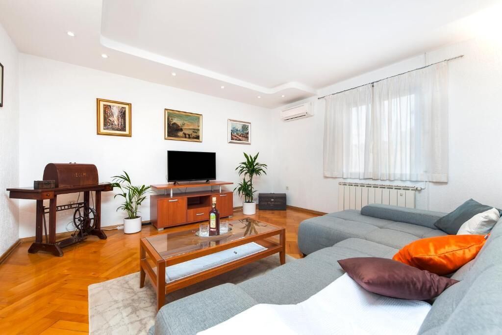 A modern living room with a sofa, a coffee table, a television, and decorative items.
