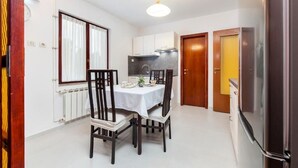 A compact kitchen with a dining table, chairs, a refrigerator, and a window with curtains. - Perfect 2-bedroom apartment with AC in beautiful Rovinj (Rovinj)