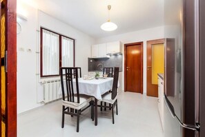 A compact kitchen with a dining table, chairs, a refrigerator, and a window with curtains. - Perfect 2-bedroom apartment with AC in beautiful Rovinj (Rovinj)