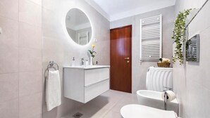 A modern bathroom with a white vanity, a round mirror, a toilet, and a shower area. - Perfect 2-bedroom apartment with AC in beautiful Rovinj (Rovinj)