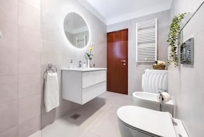 A modern bathroom with a white vanity, a round mirror, a toilet, and a shower area. - Perfect 2-bedroom apartment with AC in beautiful Rovinj (Rovinj)