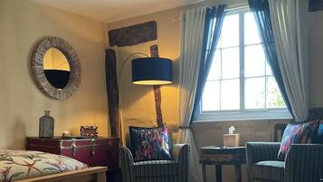 Una habitación acogedora con cama, una silla, una mesita y una lámpara.
