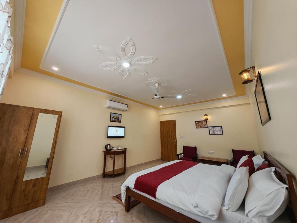 Una habitación de hotel con cama, escritorio, silla, televisor y ventilador de techo.