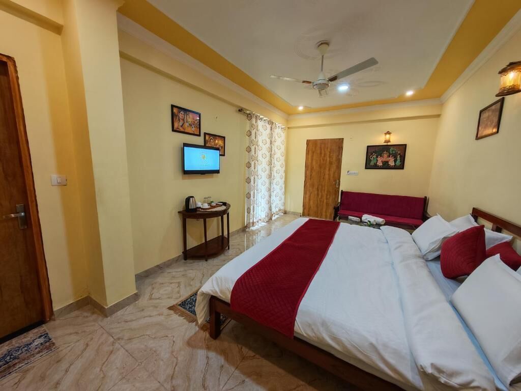 Una habitación de hotel con una cama, televisión, ventilador de techo y una puerta.