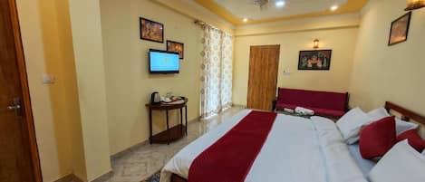 Una habitación de hotel con una cama, televisión, ventilador de techo y una puerta.
