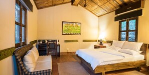 Een slaapkamer met een bed, een bureau, een stoel en een schilderij aan de muur.