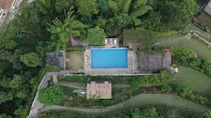 Vista aérea de una propiedad con piscina, un pequeño edificio y un jardín bien cuidado.