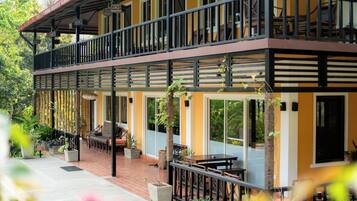 A two-story building with a balcony, outdoor seating area, and potted plants.