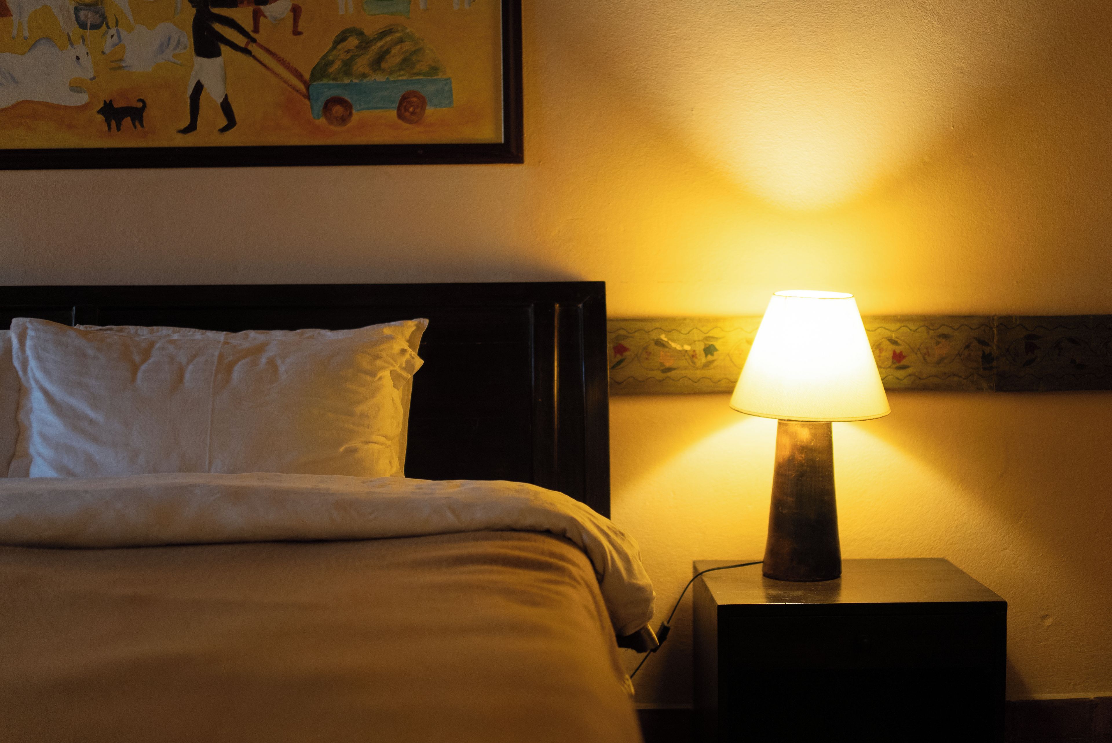 Una habitación de hotel con una cama, una mesita de noche con una lámpara y un cuadro en la pared.